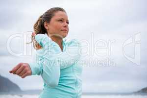 Woman performing stretching exercise on beach