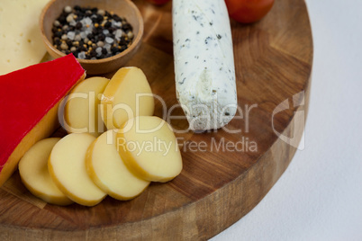 Different types of cheese, cherry tomato, spice and jam on wooden board