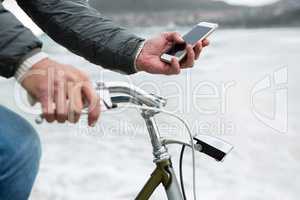 Mid section of man on bicycle using mobile phone