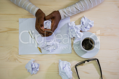 Close-up of graphic designer crumpling paper at his desk