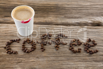 Coffee beans arranged in coffee word with disposable cups
