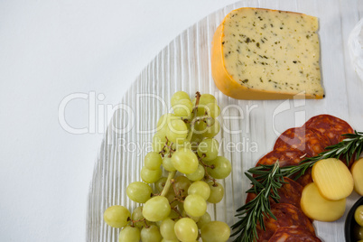 Cheese with grapes and salami on wooden board