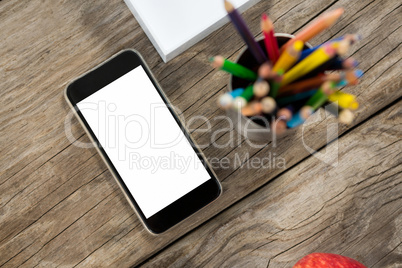 Smartphone and color pencils on wooden table