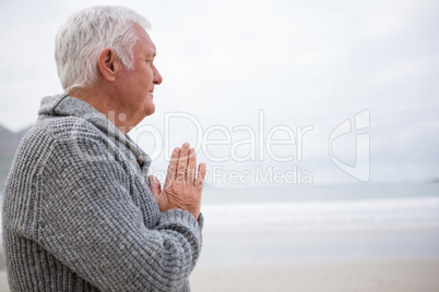 Senior man rubbing hands on beach