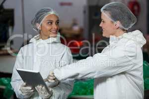 Female butchers discussing over digital tablet
