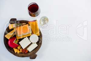 Glasses of wine with variety of cheese on wooden plate