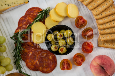 Variety of cheese with grapes, olives, salami, and crackers