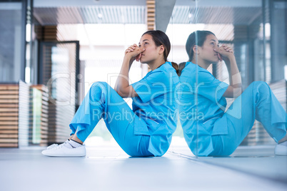 Worried nurse sitting on floor