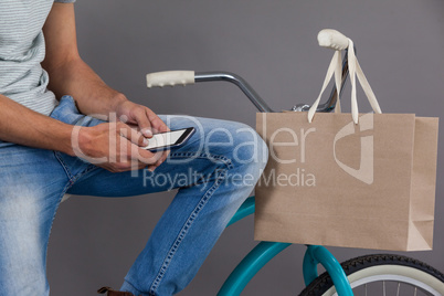 Man sitting on a bicycle and using mobile phone