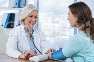 Female doctor checking blood pressure of a patient