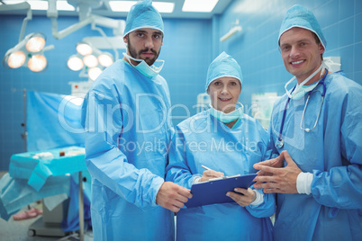 Male and female surgeon discussing over clipboard in operation theater