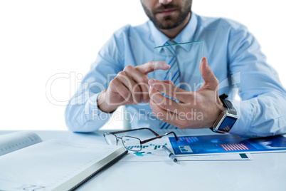 Businessman sitting at table touching a glass sheet