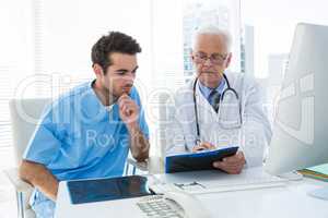 Surgeon and doctor discussing over clipboard