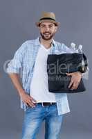 Man in fedora hat holding a bag full of plastic bottles