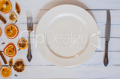 white empty dining plate with cutlery on a white wooden surface