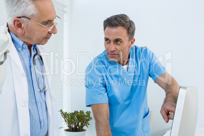 Surgeon and doctor discussing over personal computer