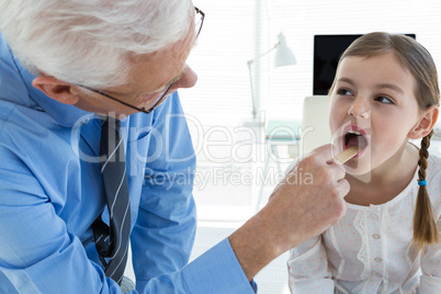 Doctor examining patient throat by using tongue depressor