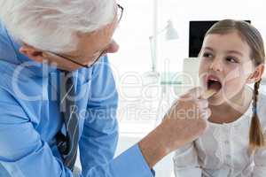 Doctor examining patient throat by using tongue depressor