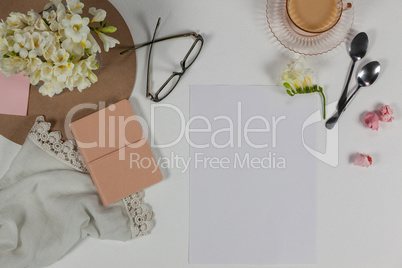 Cup of tea, spoons, spectacles, diary, cloth, blank page, paper balls and flowers