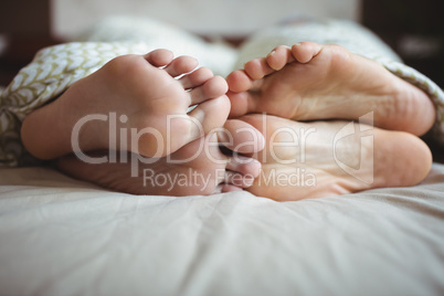 Couple showing their feet while lying on a bed