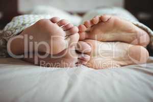 Couple showing their feet while lying on a bed