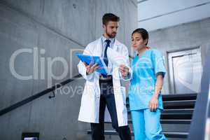 Doctor and nurse discussing over a report while climbing down stairs
