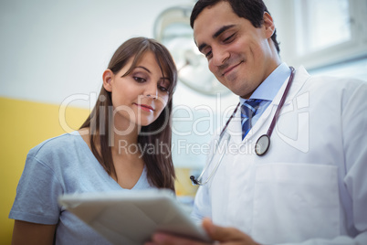 Doctor assisting female patient on digital tablet