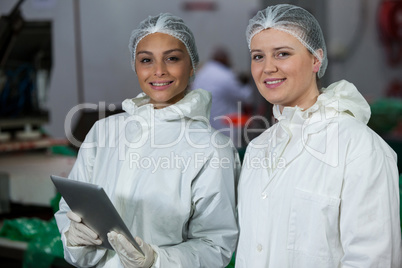 Female butchers standing at meat factory