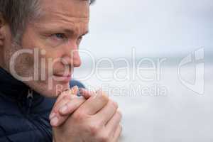Thoughtful man with hands clasped at the beach