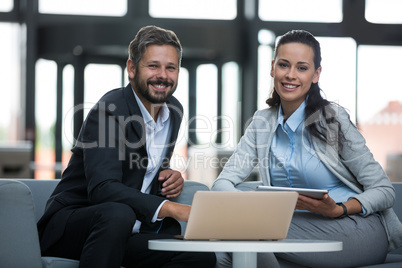 Happy businesspeople sitting with laptop