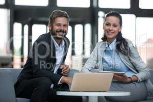 Happy businesspeople sitting with laptop