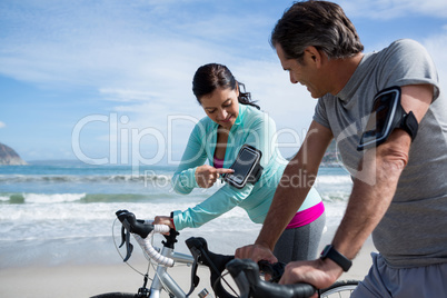 Couple leaning on bicycle while using mobile phone