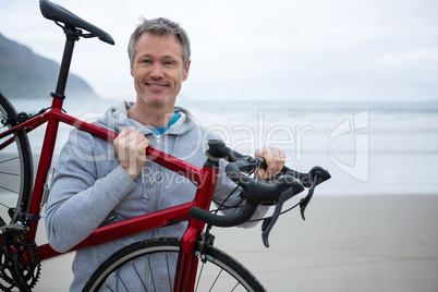 Man carrying bicycle on beach