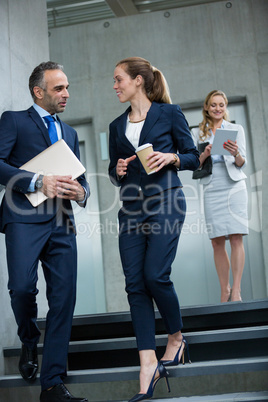 Business colleagues talking to each other while walking down stairs