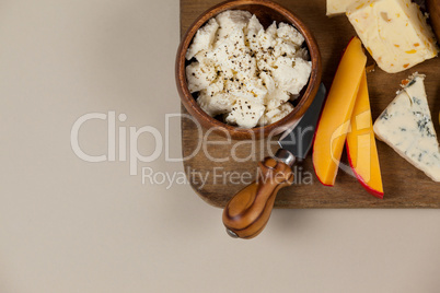 Different cheese and knife on wooden board