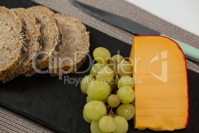 Brown bread, grapes and gouda cheese on slate board