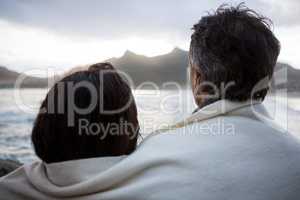 Rear view of couple wrapped in shawl on beach