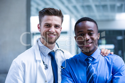 Smiling doctor with businessman standing in the hospital