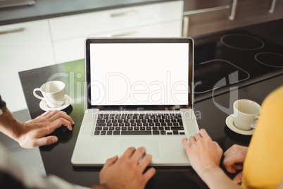 Couple using laptop in the kitchen