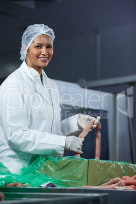 Female butcher processing sausages