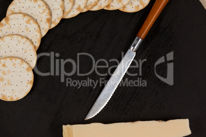 Slice of cheese with crispy biscuits and knife