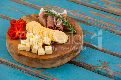 Cheese cubes, capsicum, meat, rosemary and biscuits on wooden board