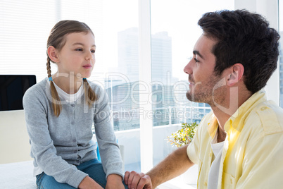 Girl sitting on the examination table with her father