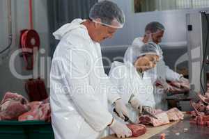 Butchers cutting meat at meat factory