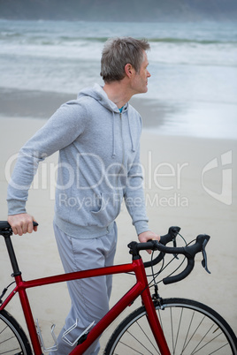 Thoughtful man standing with bicycle on beach Thoughtful man standing with bicycle on beach