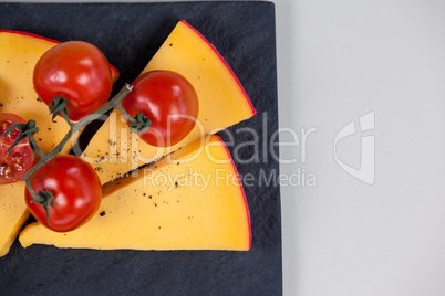 Cheese and tomatoes on slate board on white background