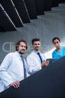 Doctor holding digital tablet standing on staircase with colleagues