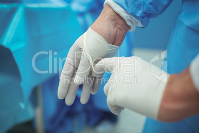 Male surgeon removing surgical gloves in operation theater