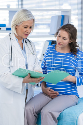 Doctor showing medical report to pregnant woman