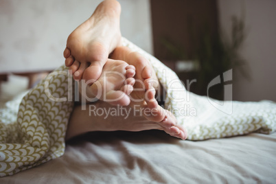 Couple showing their feet while lying on a bed